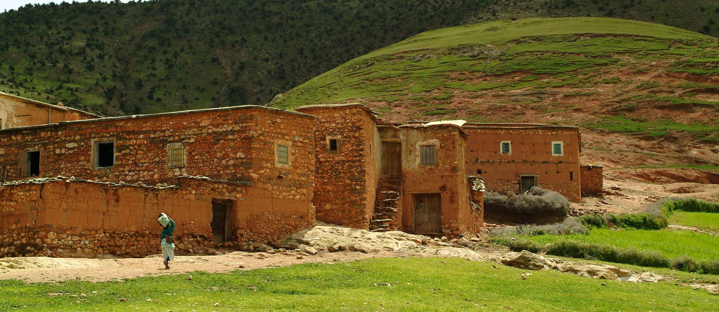 Berber woman walking in front of Berber homes